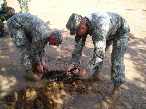 2003 Jeep TJ - Soldiers are digging in the dirt with shovels.