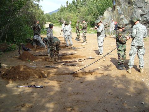 2003 Jeep TJ - Military personnel engaged in excavation work outdoors, with tools and debris scattered around.