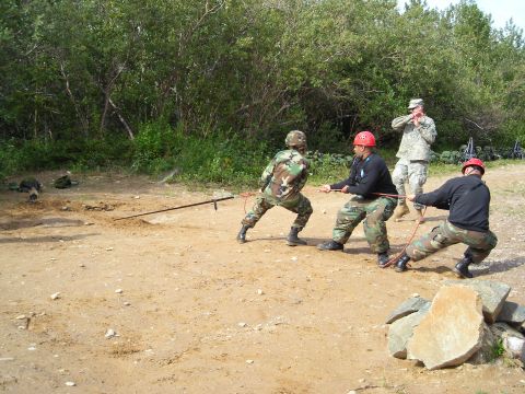2003 Jeep TJ - Soldiers participate in a training exercise, pulling on a rope in a dirt and rocky terrain with trees in the background.