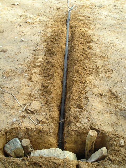 2003 Jeep TJ - A trench has been dug, revealing a cable and some wooden stakes in the soil.