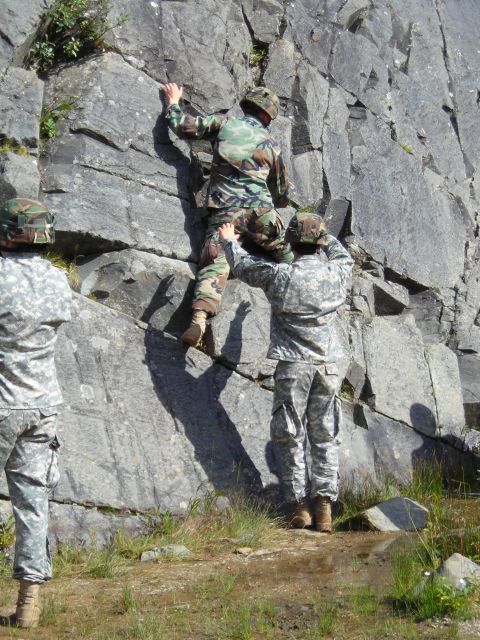 2003 Jeep TJ - Military personnel ascend a challenging rock face during an outdoor training exercise.