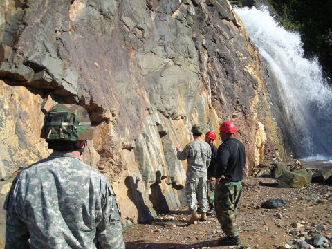 2003 Jeep TJ - A group of people examine a rocky cliff face with a waterfall cascading nearby.