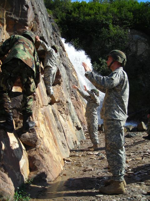 2003 Jeep TJ - Soldiers navigate a challenging climb up a rocky cliff beside a cascading waterfall during training.