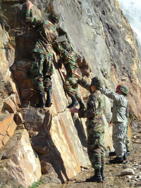 2003 Jeep TJ - Military personnel ascend a rocky incline, demonstrating teamwork and climbing skills in an outdoor training exercise.