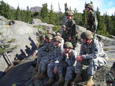 2003 Jeep TJ - Soldiers take a break in a , natural environment, surrounded by trees and rocky terrain.