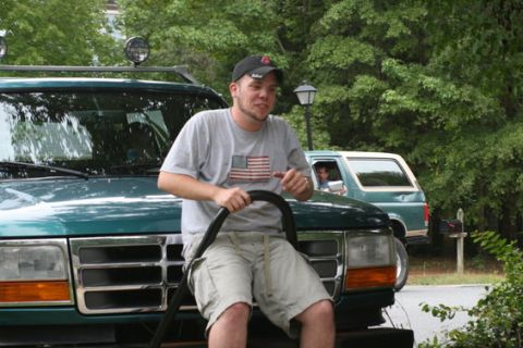 1996 Ford Bronco - A man sits on the hood of a 1996 Ford Bronco, with another Bronco visible in the background.