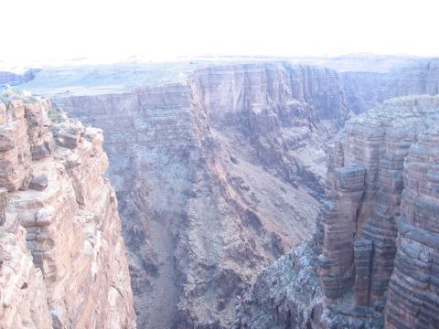 1995 Ford Probe - A vast canyon vista with dramatic, layered rock formations stretching into the distance under a hazy sky.