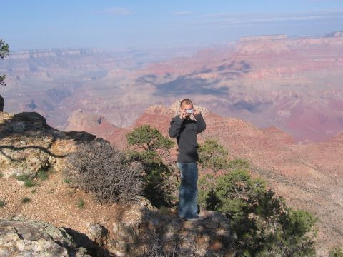 1995 Ford Probe - Man photographs the vast Grand Canyon from a rocky overlook on a clear day.