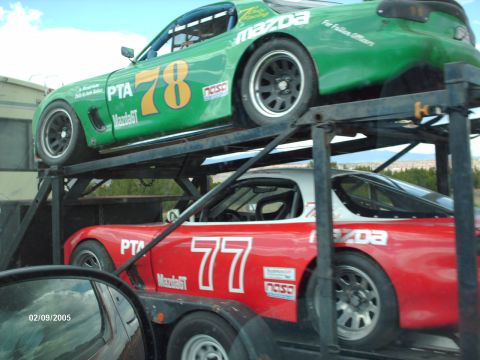 1995 Ford Probe - Two Mazda RX-7 race cars, one red and one green, are transported on a car hauler.