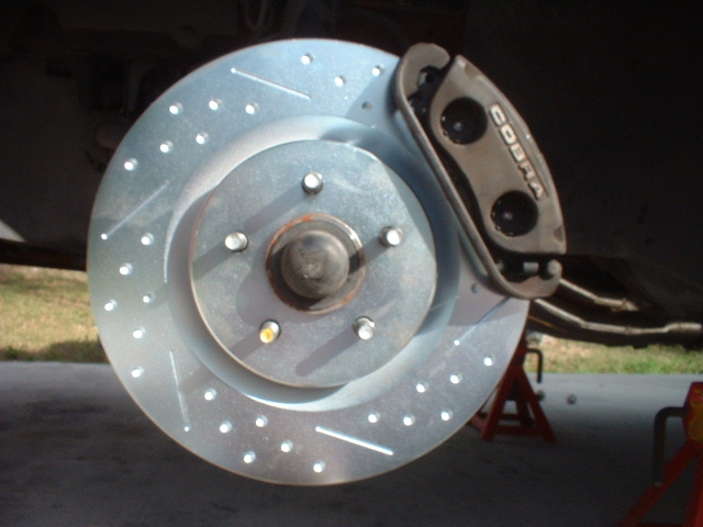 Close-up of a Cobra brake caliper and drilled rotor on a car