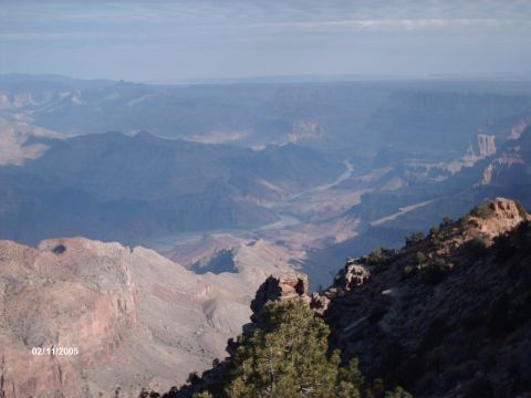 1995 Ford Probe - A wide view of the Grand Canyon shows the Colorado River winding through the vast landscape under a hazy sky.