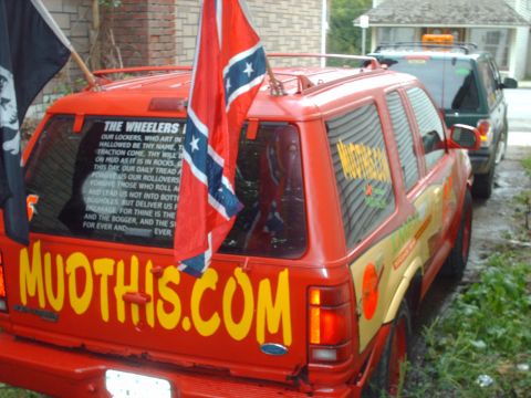 1991 Chevrolet Blazer - A red SUV displays large yellow lettering and flags, with another vehicle visible behind it.