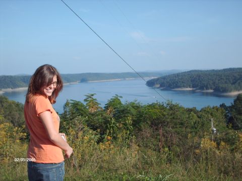 1995 Ford Probe - A woman smiles while looking back over her shoulder at a scenic lake view on a sunny day.
