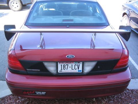 2001 Ford Crown Victoria - Rear view of a red 2001 Ford Crown Victoria, modified with a large spoiler and a Wisconsin license plate.