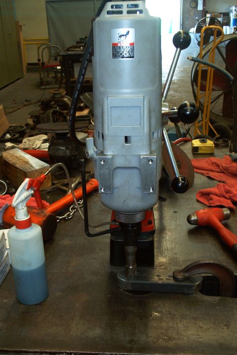 1983 Ford Bronco - Drill press with various tools and supplies on a workbench in a workshop.