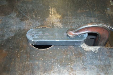 1983 Ford Bronco - A metal part is secured by a clamp on a rough surface, possibly for fabrication or repair.