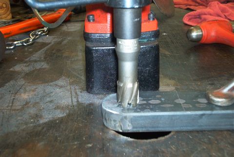 1983 Ford Bronco - A hole is being drilled into a metal plate with a rotary tool, part of a larger metalworking process.