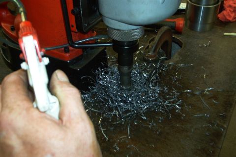 1983 Ford Bronco - Metal shavings are produced as a drill bit cuts into a surface, with a spray bottle in hand.