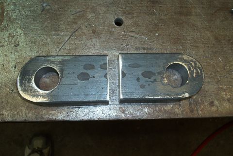 1983 Ford Bronco - Two metal brackets, possibly for a brushguard or bumper, lie on a workbench.