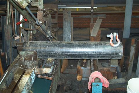 1983 Ford Bronco - Metal pipe being cut on a band saw in a workshop setting.