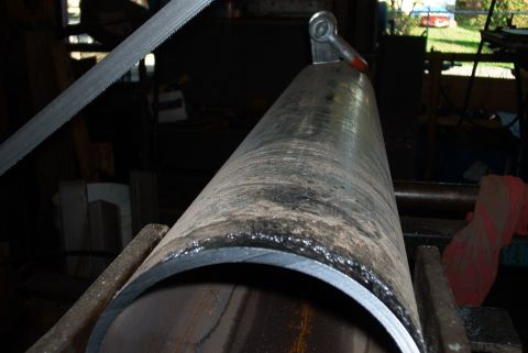 1983 Ford Bronco - A metal pipe is being cut with a band saw in a workshop setting.