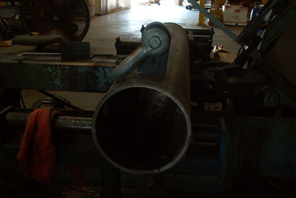 Metal pipe with clamp mechanism on industrial machinery, red cloth nearby