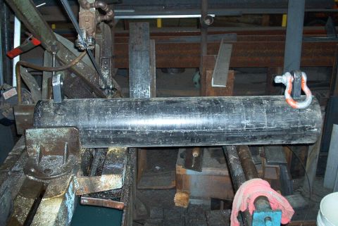 1983 Ford Bronco - A metal pipe is positioned on a band saw, awaiting a cut. The machine appears to be in a workshop setting.