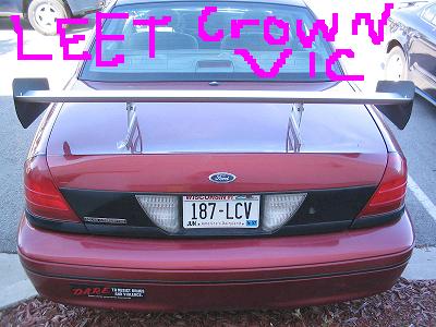 2001 Ford Crown Victoria - Rear view of a red 2001 Ford Crown Victoria, modified with a large spoiler and aftermarket decals.