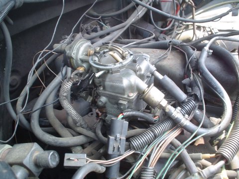 1984 Ford Bronco - Close-up of a vehicle's engine bay, focusing on the carburetor and associated hoses and wires.