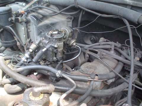 1984 Ford Bronco - Close-up view of a vehicle's engine compartment, focusing on the carburetor and associated components.