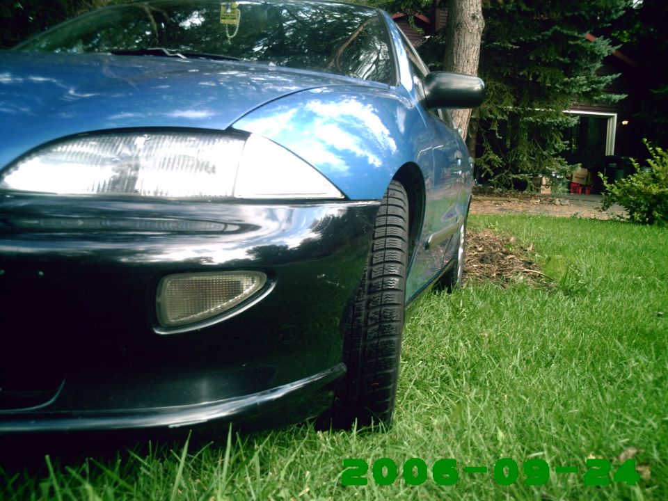 blue sedan parked on grass, front corner visible