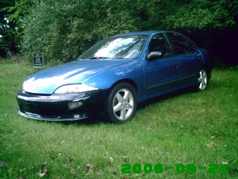 1996 Chevrolet Cavalier - A blue sedan with a contrasting black front bumper sits on a grassy lawn, with a 'For Sale' sign nearby.