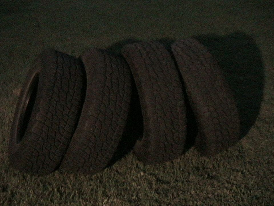 Four tires laid on grass, one partially visible