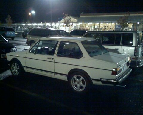 1987 Volkswagen Golf - A white Volkswagen sedan is parked in a lot at night, viewed from the rear three-quarter angle.