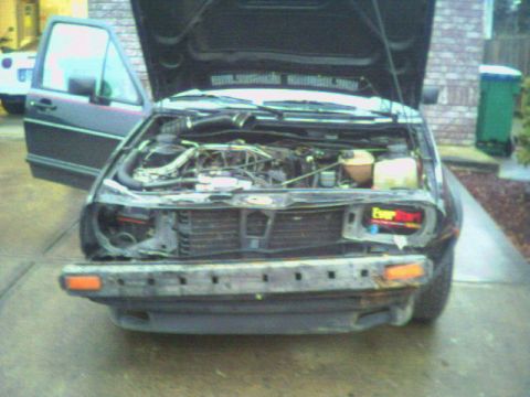1987 Volkswagen Golf - The engine bay of a 1987 Volkswagen Golf is shown with the hood open and the front bumper removed.