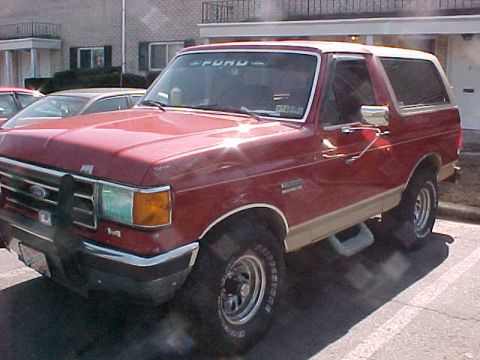 1990 Ford Bronco - This red Ford Bronco with tan two-tone trim is seen from the front 3/4 angle.