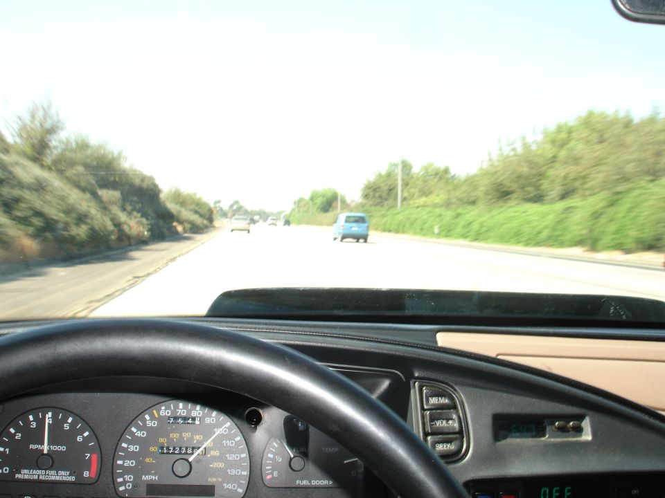View from inside a car, looking at the dashboard and the road ahead with other cars driving