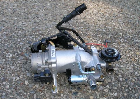 2001 Ford Crown Victoria - A Ford throttle body assembly, likely removed for maintenance or replacement, is shown on a textured ground.