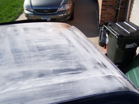 1986 Ford Bronco - A car roof is covered in white compound, with a silver sedan parked behind it.