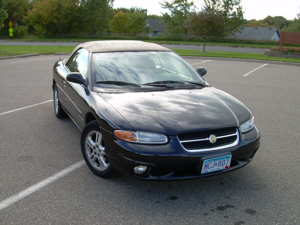 Black Chrysler Sebring convertible with tan top, front 3/4 view in parking lot