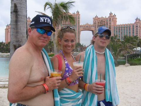1994 Ford Bronco - Three people enjoy drinks on a sandy beach with a large, ornate hotel in the background.