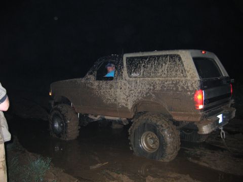 1994 Ford Bronco - Muddy SUV navigating a difficult off-road path in the dark.