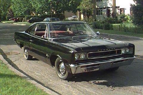 1993 Ford Taurus - This 1967 Dodge Coronet is parked on a street with trees and houses in the background.