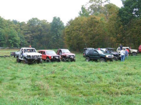 1995 Ford Bronco - A group of off-road vehicles are gathered in a field on an overcast day.