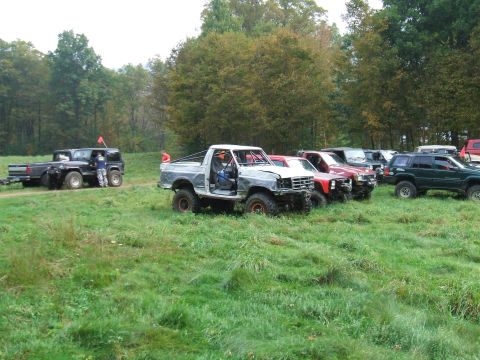 1995 Ford Bronco - Several off-road vehicles, including a 1995 Ford Bronco, are parked in a grassy field.