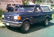 1991 Ford Bronco - A dark blue 1991 Ford Bronco is shown from the front three-quarter angle.