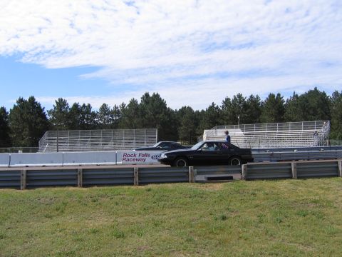 1989 Ford Mustang - Two cars are lined up at Rock Falls Raceway, ready for a drag race.