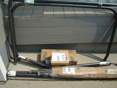 1993 Ford Bronco - Unboxed automotive parts, including metal tubing and packaged components, are arranged on a concrete surface.