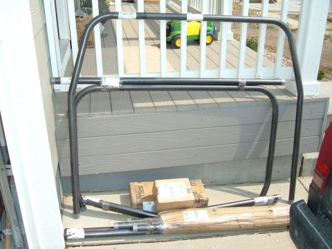1993 Ford Bronco - Roll cage components are laid out on a deck, with several cardboard boxes and a toy tractor visible in the background.