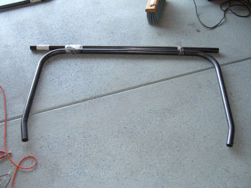 Bare steel roll bar main hoop and straight tube taped together on a garage floor
